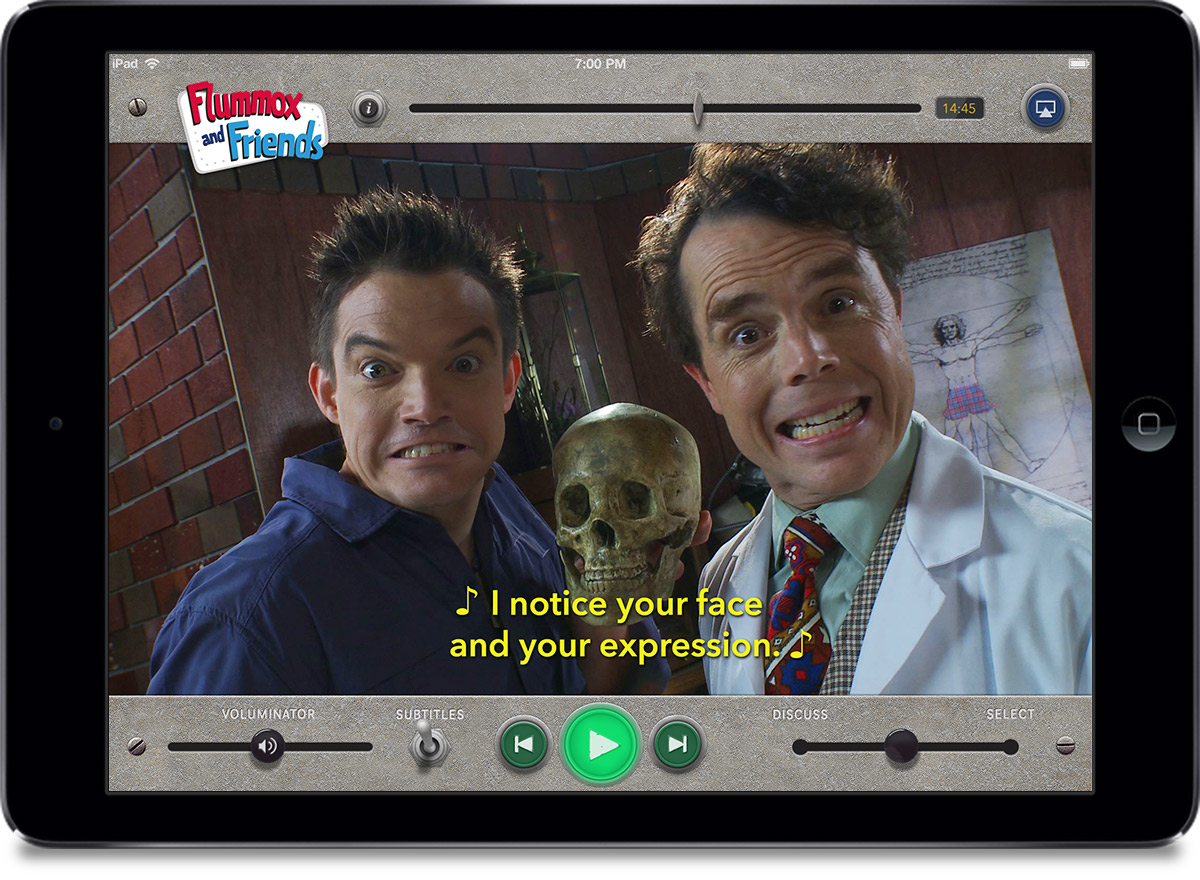 Early generation iPad showing the Flummoxvision app. Subtitles are active. We see two faces grimacing at the camera, with the subtitle: “♪ I notice your face and your expression ♪”